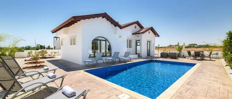 A modern house with a swimming pool, outdoor seating, and a patio area.