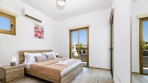 Un dormitorio con cama de madera, mesitas de noche, unidad de aire acondicionado, un cartel en la pared y vistas a través de una puerta.