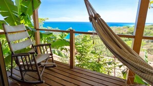 A wooden deck with a hammock and a rocking chair overlooking a coastal view. - Anamaya (Cóbano)