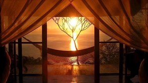 A room with a large window, a bed, and a view of the sunset. - Anamaya (Cóbano)