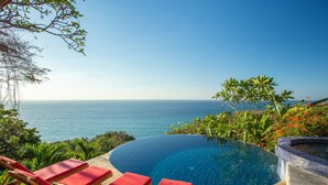A pool with a view of the ocean, surrounded by lounge chairs and tropical plants. - Anamaya (Cóbano)
