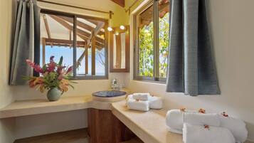 Bathroom with a window offering a view of the outdoors, featuring a sink, stool, and towels.