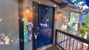 A wooden house with a dark blue front door, a welcome sign, and a porch with a railing. - Sedona Red Rock Garden of Paradise, Pets friendly and Hot Tub (Sedona)