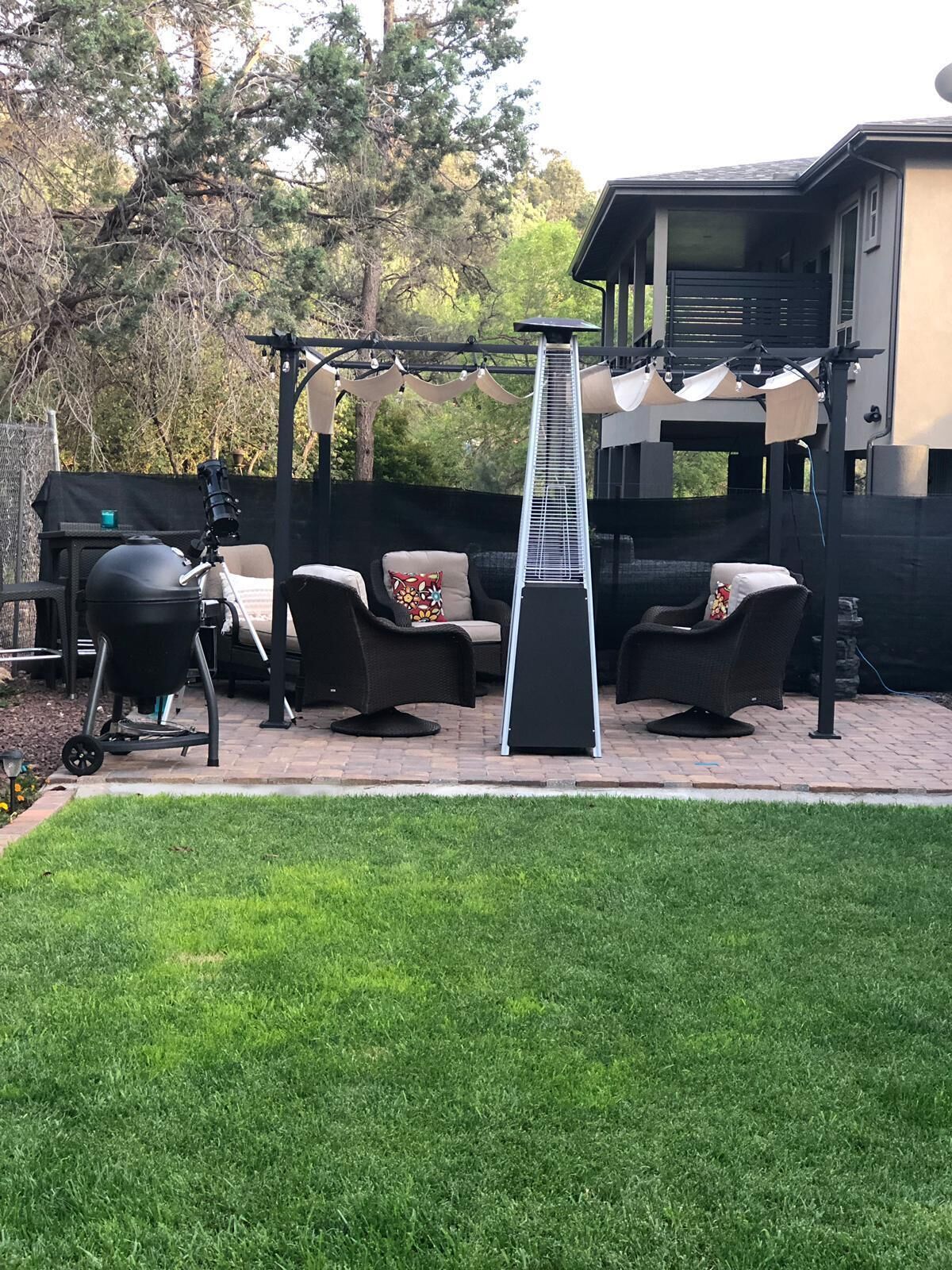 Een terras met buitenmeubilair, een barbecue en een pergola.