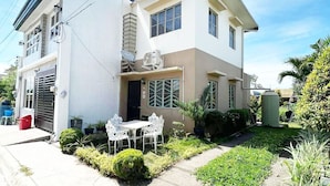 A two-story house with a balcony, a small garden, and a patio with outdoor furniture. - Town House Next to the Beach - TALOMO TORIL DAVAO (Talomo)