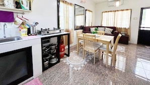 A compact kitchen with a gas stove, sink, and storage cabinets. A dining area with a table and chairs is adjacent to the kitchen. - Town House Next to the Beach - TALOMO TORIL DAVAO (Talomo)