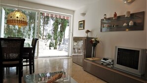 A living room with a glass coffee table, a television, a fireplace, and a large window with a view of trees. - Apartment in Rovinj with Terrace, Air condition, WIFI, Dishwasher (4285-2) (Rovinj)