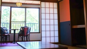 Una habitación japonesa tradicional con suelo de tatami, una mesa baja, sillas y biombos de papel.