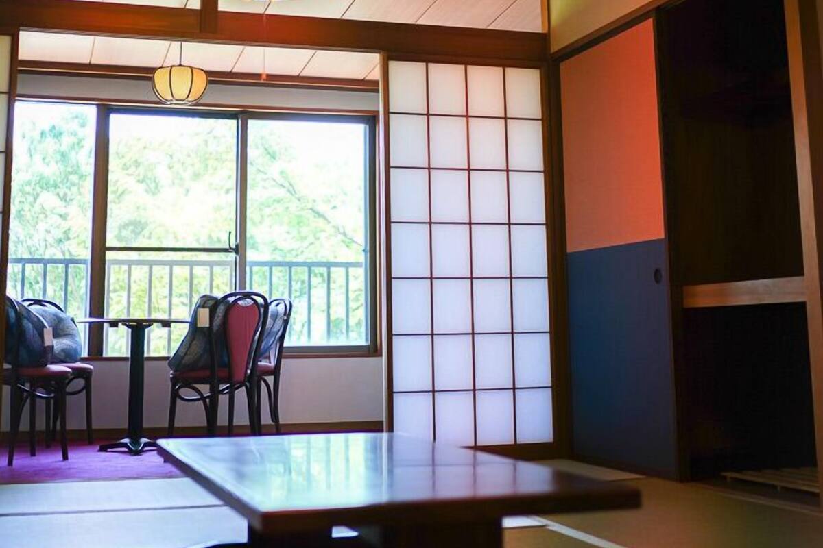 Ein traditioneller japanischer Raum mit Tatami-Böden, einem niedrigen Tisch, Stühlen und Shoji-Schiebetüren.