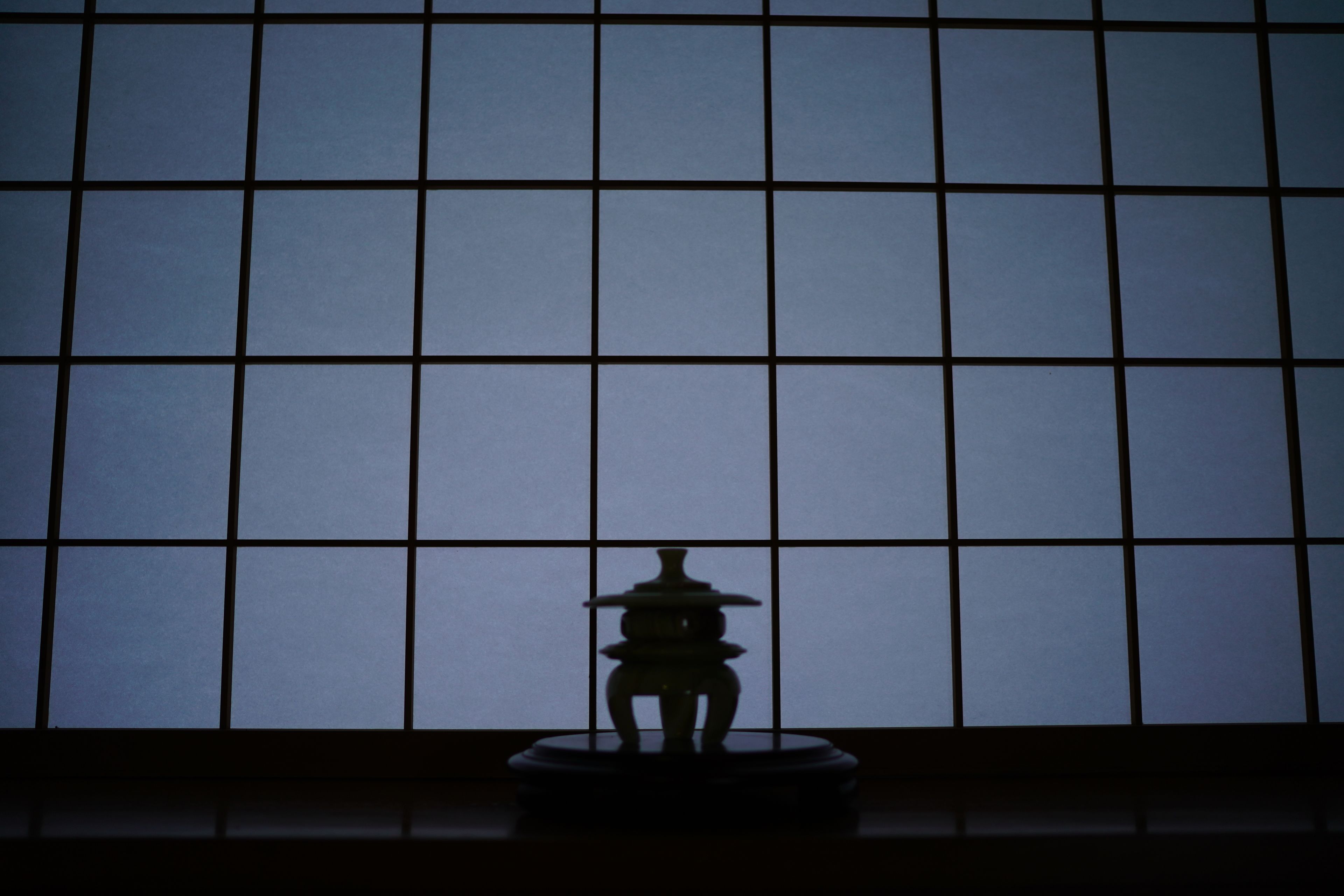 A traditional Japanese tea ceremony room with tatami flooring and a shoji screen backdrop.