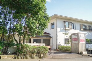 A building with a white exterior, a small entrance gate, and a signboard. - Ryokan Kazenomori (Sakai)