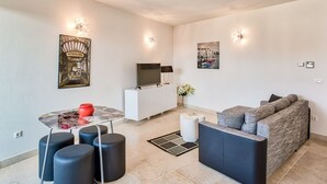 Un salon moderne avec un canapé, une table basse et un téléviseur posé sur un meuble blanc.