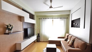 Una sala de estar moderna con una televisión de pantalla plana, un sofá, una mesa de centro y un ventilador de techo.