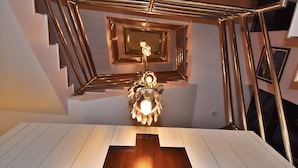 Una escalera moderna con diseño geométrico y una lámpara central.