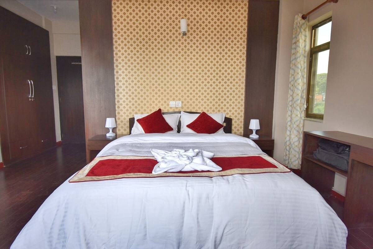 A neatly made bed with a red and white bedspread, two red pillows, and a white towel on the bed.