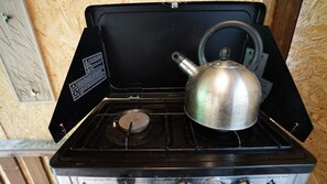 A portable gas stove with a kettle on it, placed on a wooden surface. - Beehive @ Westcote Glamping- Campsite (Hawick)