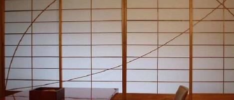 A traditional Japanese room with tatami flooring, a low wooden table, and a sliding shoji screen.