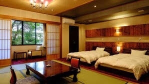 A traditional Japanese-style room with tatami flooring, two beds, a low table, and a sliding door. - Misasaonsen Kouraku (Misasa)