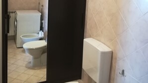 A bathroom with a toilet, bidet, and a shower area. - Two-room apartment for rent (Ravenna)