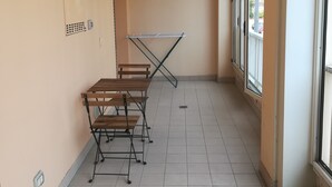 A corridor with a table and benches, a radiator, and a window with a view of the outside. - Two-room apartment for rent (Ravenna)