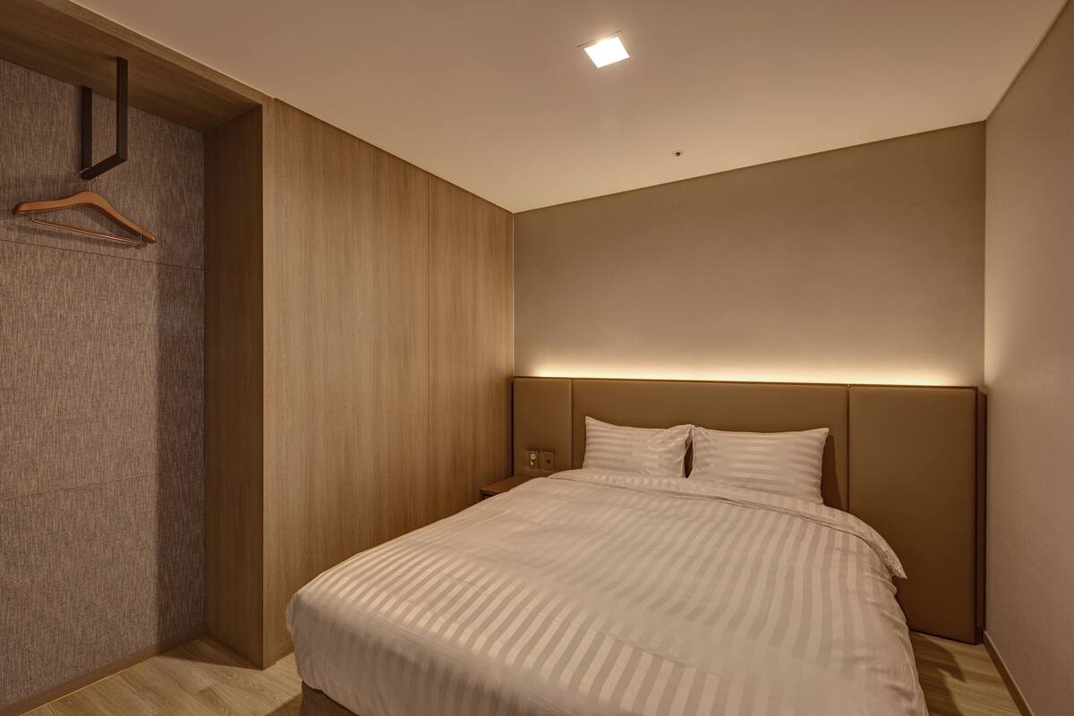 Un dormitorio moderno con una cama grande, paneles de madera en las paredes y una lámpara empotrada en el techo.
