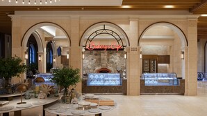 A bakery cafe with a stone wall and arched entrance, marble tables, and a display case with baked goods. - Sol Beach Jindo (Jindo)
