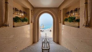 A corridor with a view of the beach, featuring a bench, potted plants, and wall-mounted lights. - Sol Beach Jindo (Jindo)