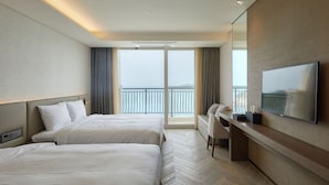 A hotel room with two beds, a desk, a TV, and a balcony with a view. - Sol Beach Jindo (Jindo)