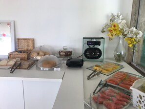 Montaje de bufé con diversos alimentos, una máquina de café y flores decorativas.