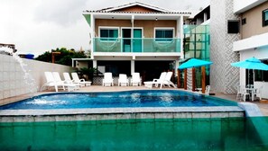 Una piscina al aire libre, sombrillas, sillones reclinables de piscina