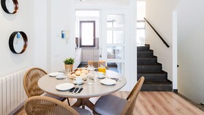 Un comedor con una mesa redonda, sillas de mimbre y una disposición para el desayuno.