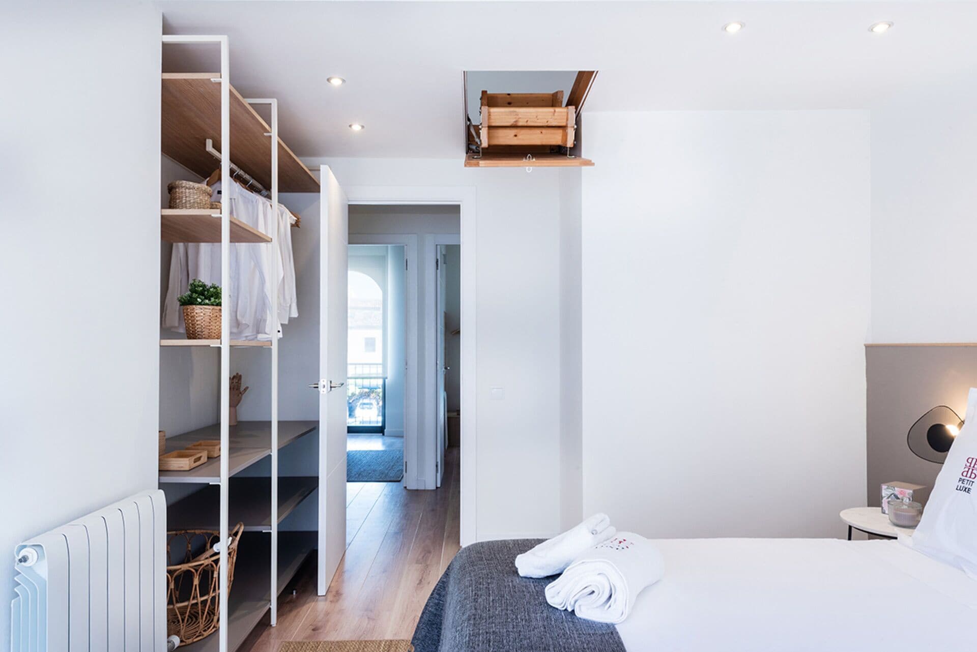 A modern bedroom with a bed, a wardrobe, and a small table with a lamp.