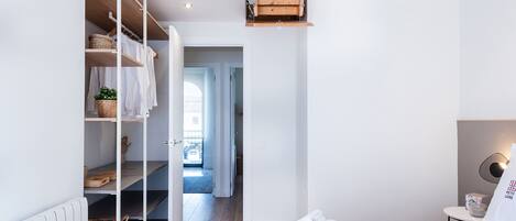 A modern bedroom with a bed, a wardrobe, and a small table with a lamp.