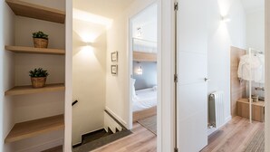 Un pasillo de hotel con estantes de madera, una escalera, una cama y un baño con radiador.