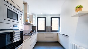 Cocina moderna con electrodomésticos de acero inoxidable, armarios blancos y ventana que proporciona luz natural.