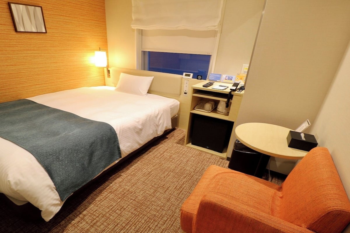 Ein Hotelzimmer mit einem Bett, einem Schreibtisch, einem Sessel und einem kleinen Tisch.