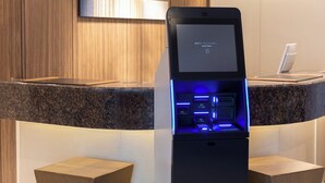 A self-service kiosk with a digital screen, located in a modern hotel lobby with wooden paneling and a granite countertop. - Keikyu EX Inn Akihabara (Tokyo)