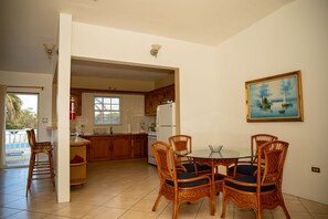 Una cocina amplia con armarios de madera, una mesa de comedor con sillas y un cuadro en la pared.