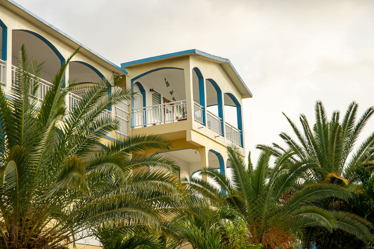 Un edificio de varios pisos con balcones, rodeado de palmeras.