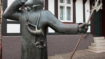 Eine Statue eines Mannes mit Stab und Schild, vor einem Gebäude mit der Nummer 12 an der Tür.