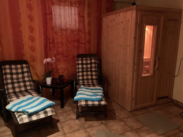 Two checkered armchairs with blue-striped cushions, a small table with a potted orchid, and a wooden cabinet with a window.