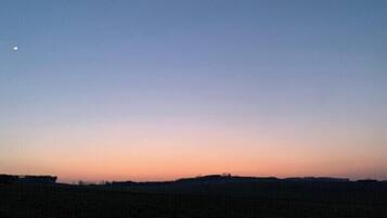 Eine flache Landschaft mit blauem Himmel und einem kleinen Mond in der oberen linken Ecke.