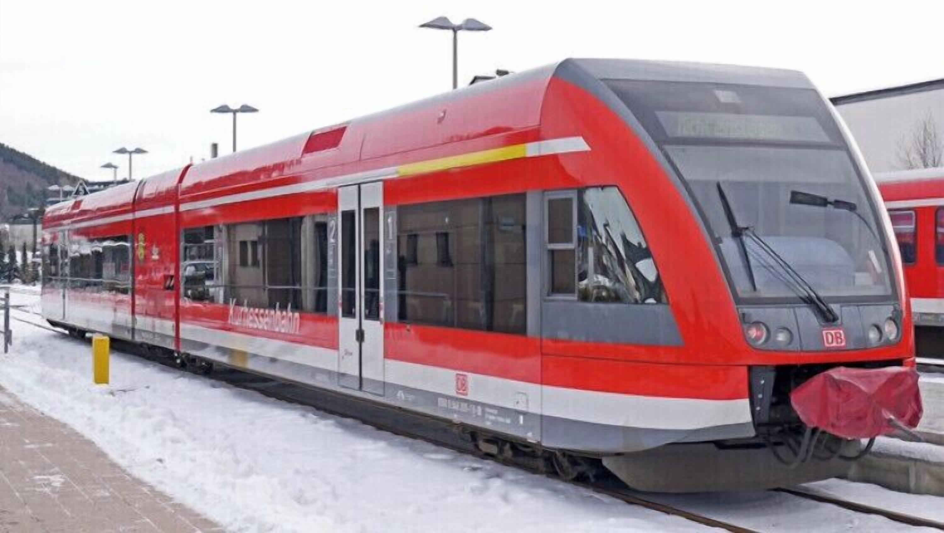 Un treno moderno con decorazioni rosse e bianche, fermo su un binario innevato.