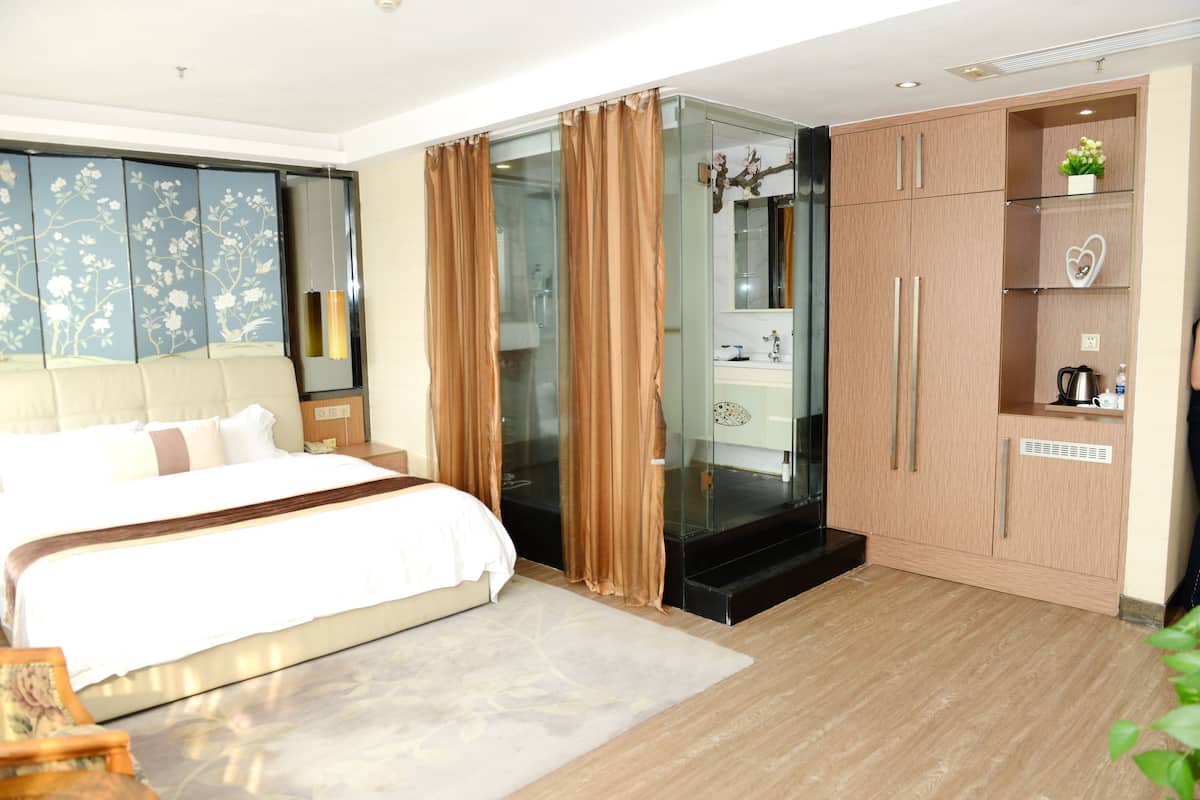 Un dormitorio moderno con una cama grande, cabina de ducha con mampara de vidrio y un armario de madera.