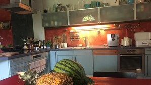 A kitchen with a red table, a pineapple, and a watermelon on a green plate. - Sommerhof in the beautiful Havelland (Märkisch Luch OTBuschow)