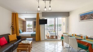 A modern hotel room with a sofa, dining table, and a view of the outside. - le Grand Foc by Interhome (Capbreton)