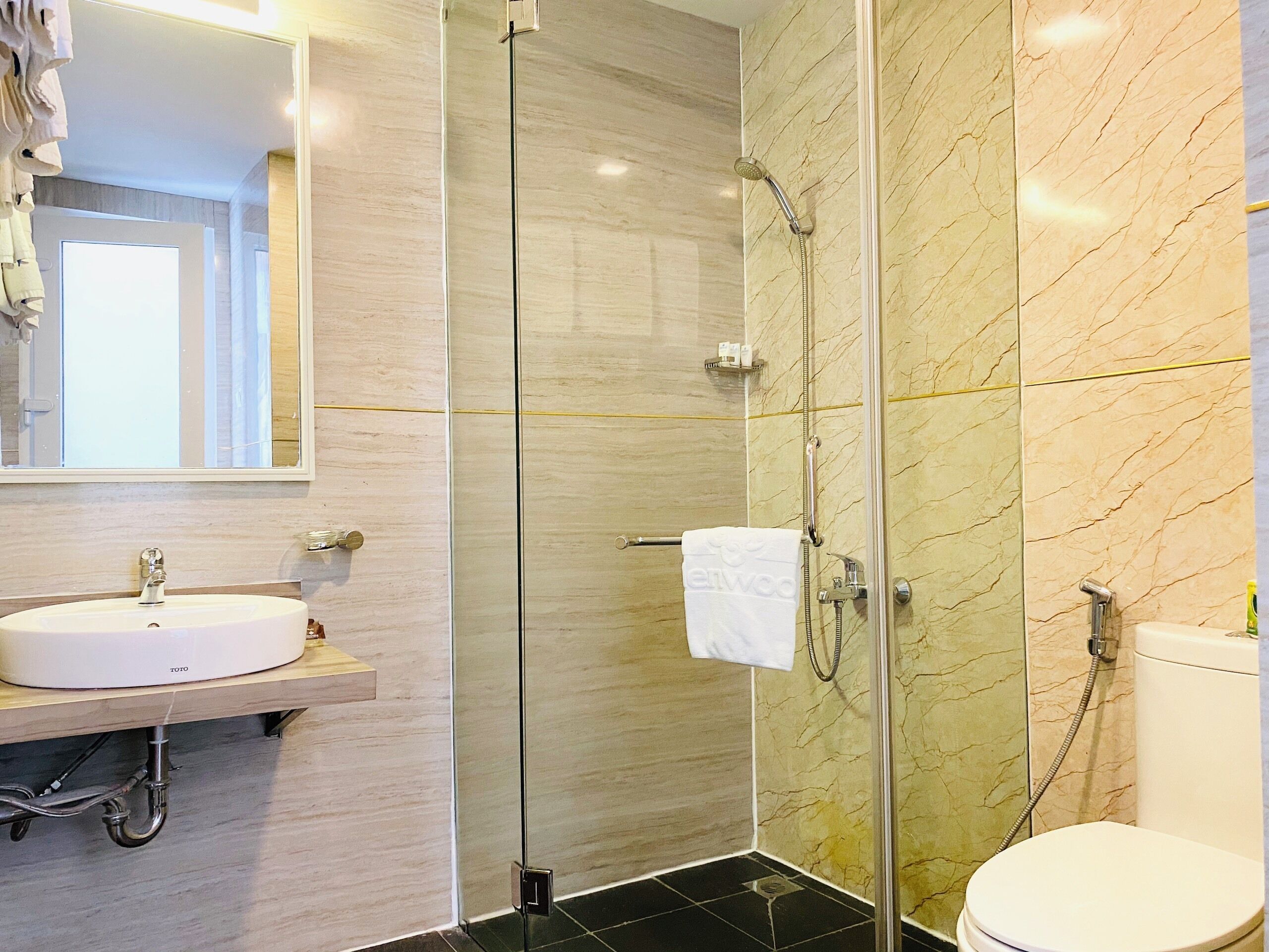 Une salle de bain moderne avec une douche à parois de verre, un lavabo blanc et des toilettes.