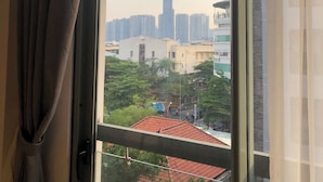 Ein Fenster mit Blick auf einen hohen Wolkenkratzer, vermutlich ein Wahrzeichen, sowie umliegende Gebäude.
