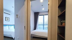 Ein Hotelzimmer mit einem Bett, einem Fenster mit Vorhängen und einem Regal mit einer Topfpflanze.