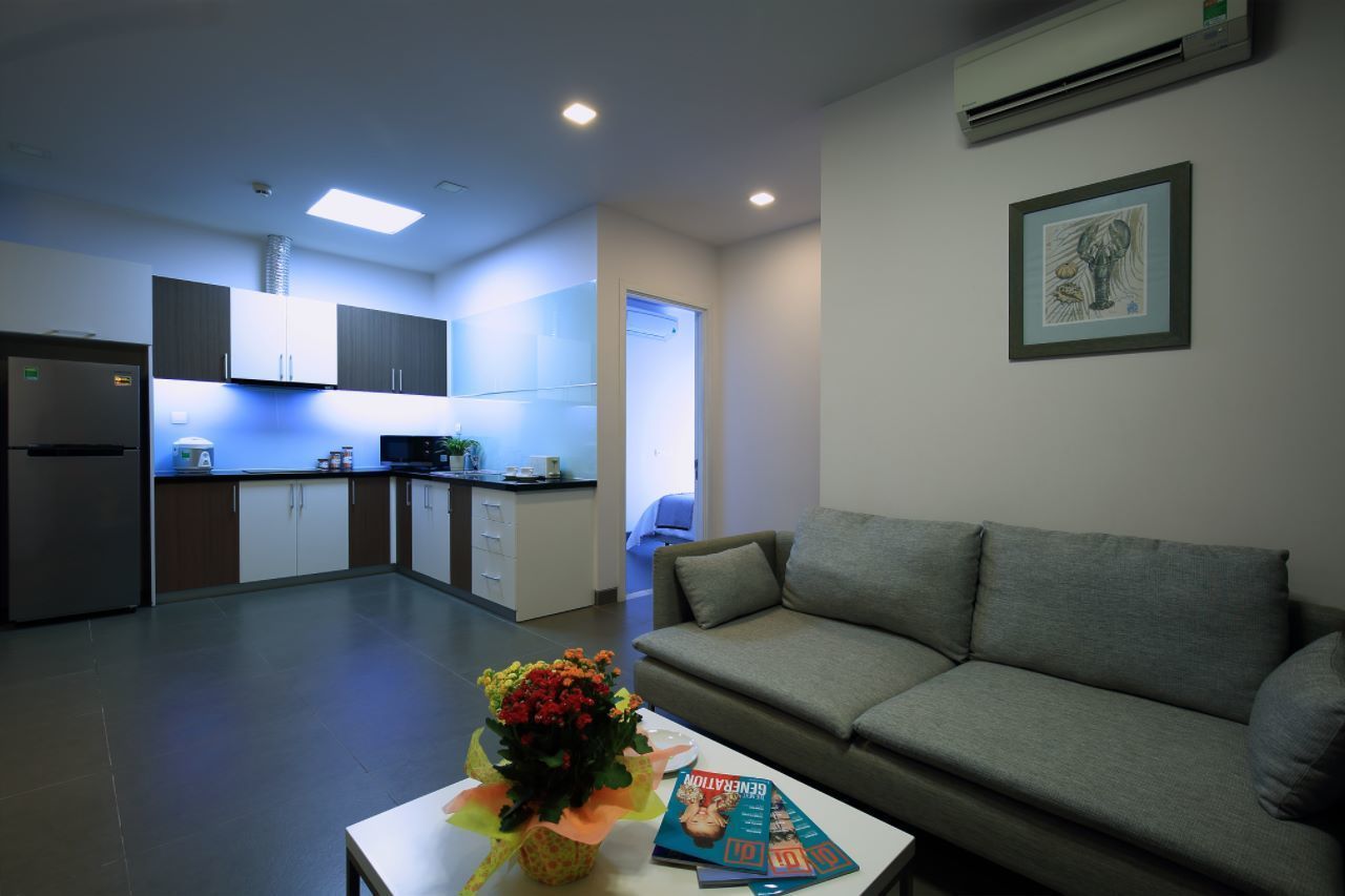 A modern living room with a grey sofa, a coffee table with a vase of flowers, and a framed picture on the wall.